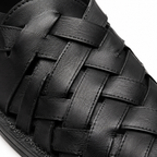 Détail du cuir tressé des sandales noires.